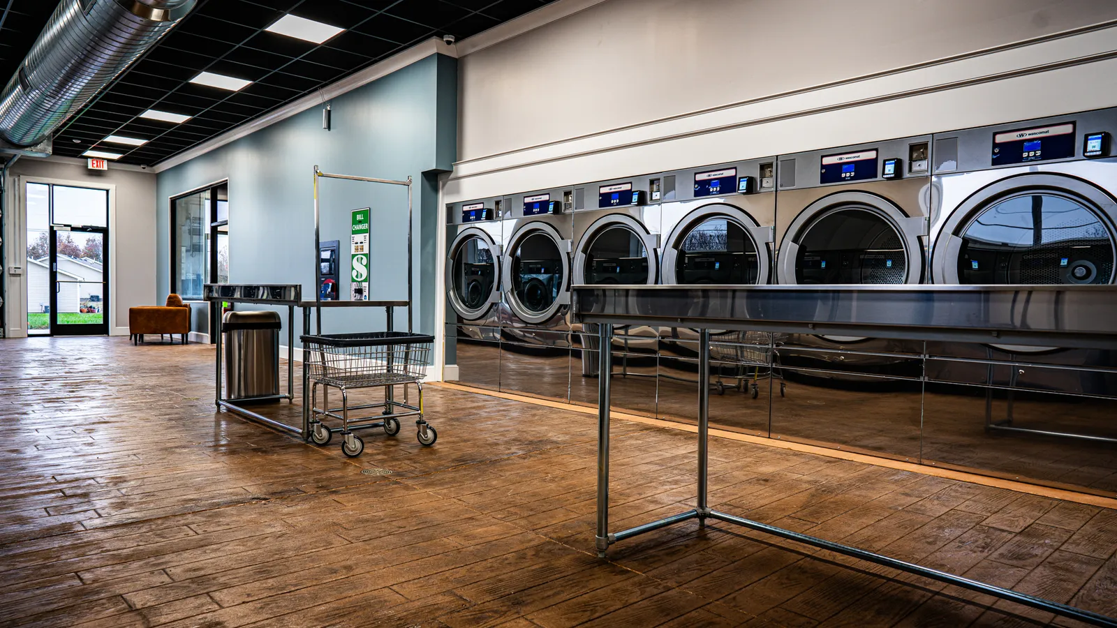 Row of commercial dryers along a laundromat wall