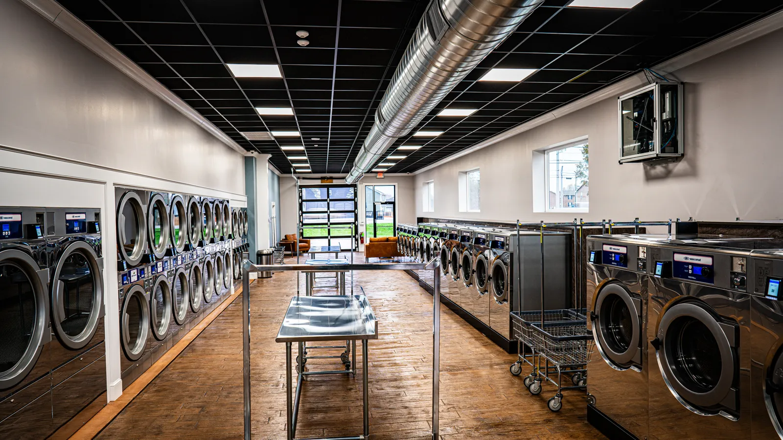 Laundromat with rows of front-load washers and a wall of dryers